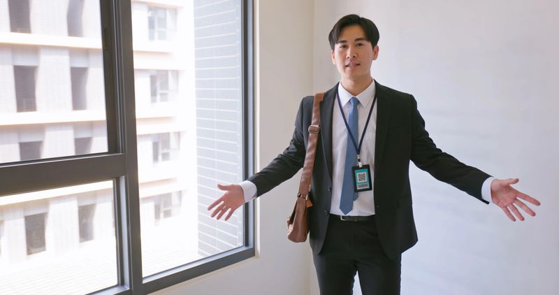 Asian professional real estate agent presents an empty apartment highlighting features and discussing details with potential buyers