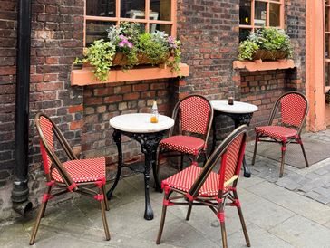Outdoor café seating with red chairs and flower boxes.