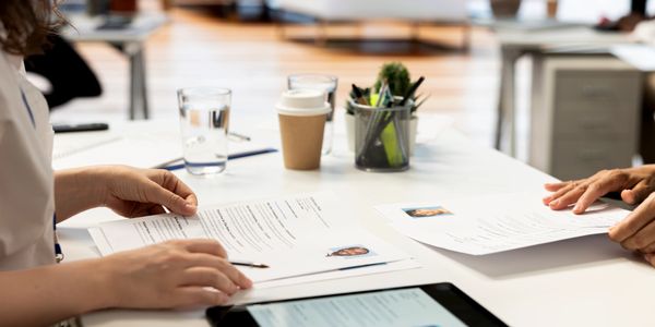 Two people reviewing resumes at a desk with coffee and water.