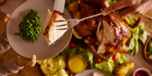 A piece of roasted turkey breast being served onto a plate with green beans.