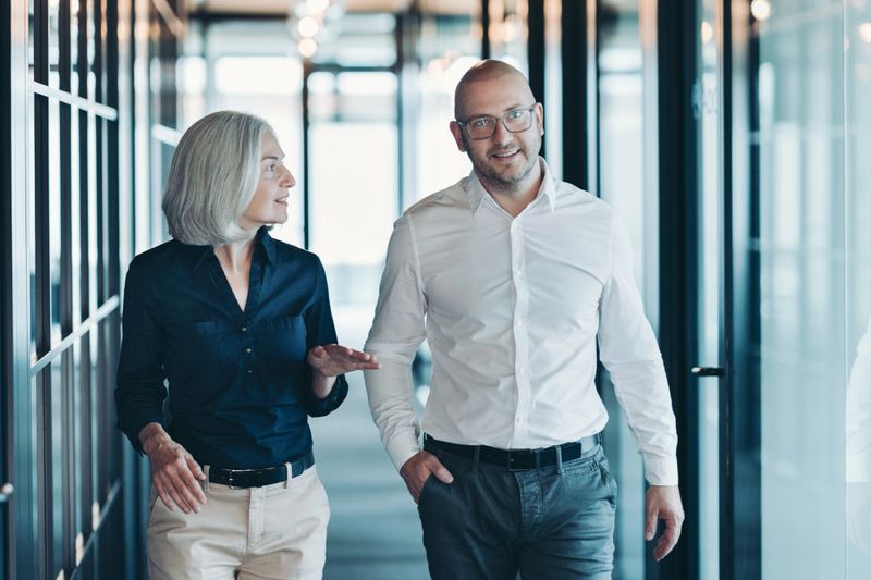 Mature businesswoman and middle age businessman walking together and talking
