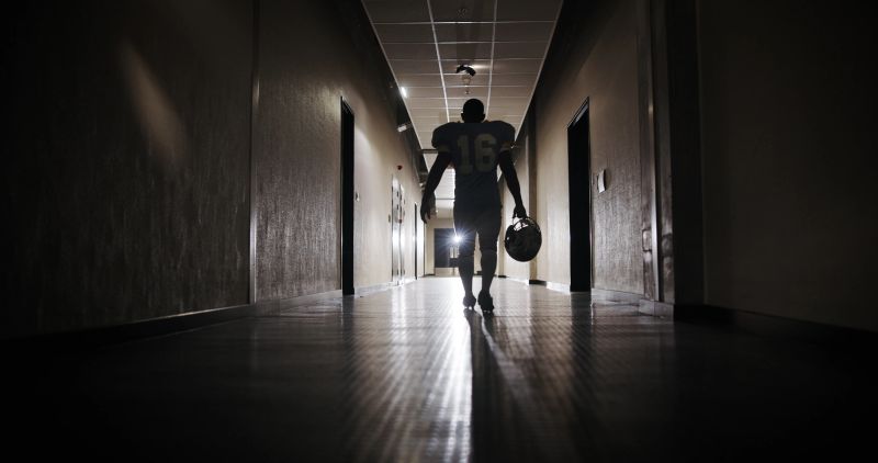 Back, football and light with man in corridor for sports competition, stadium match and game. Fitness, pro league player and athlete with person in tunnel for training, tournament and contest