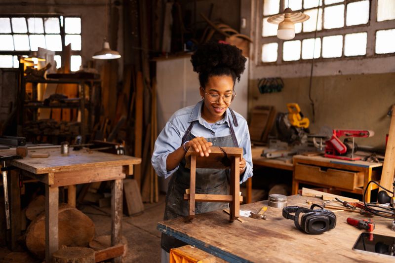Craftsperson focusing on assembling a wooden stool in an authentic and sustainable workshop.