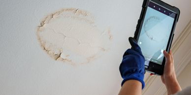 Water damage marking on ceiling being photographed.