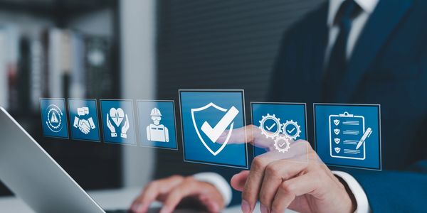 Businessman interacting with virtual safety and compliance icons on a laptop.