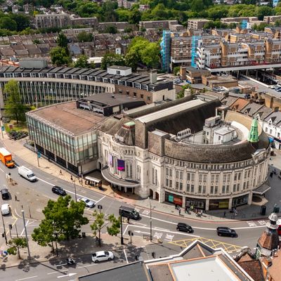 Aerial view of a curved historic building surrounded by roads and traffic in a city.