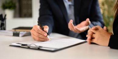 Two people discussing and signing a document at a desk.
