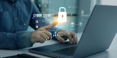 Person interacting with a laptop and cybersecurity holographic interface.