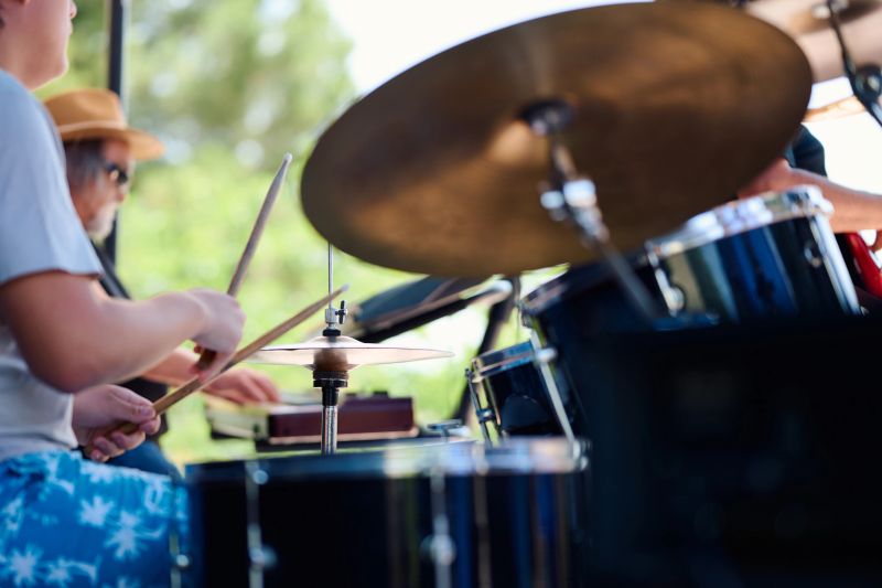 Drummers performing energetically during a vibrant outdoor concert, captivating the audience with rhythmic beats and lively music