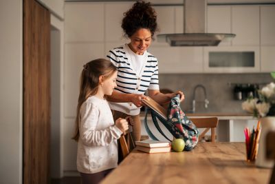 Mother and daughter packing a school bag in the kitchen.