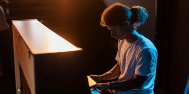 Man playing piano under moody lighting.