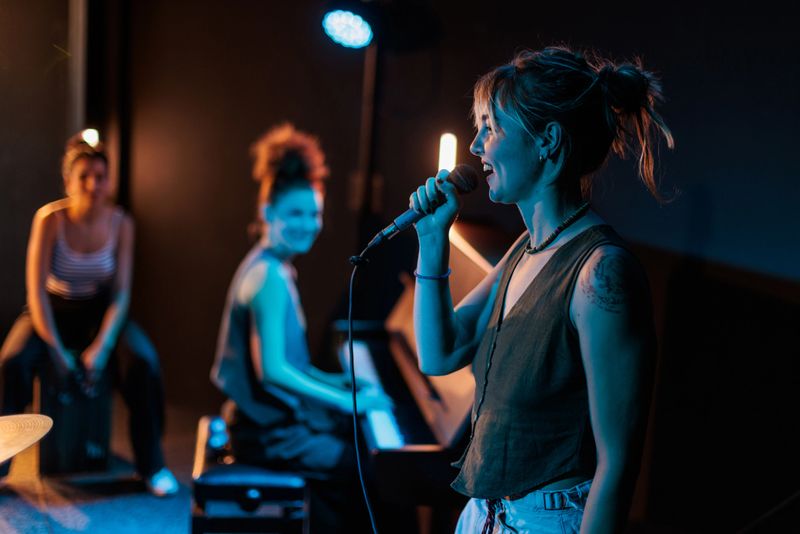 In the spotlight stands a beautiful woman singing passionately with a microphone in her hands, her expression confident and full of emotion.