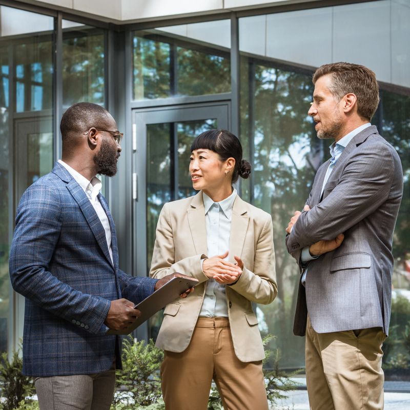 Multicultural business team having a discussion outdoor in front modern office building
