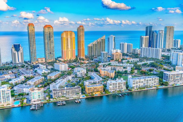 Aerial view of a coastal city skyline with tall buildings and waterfront homes.