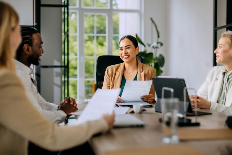 Well dressed businesswoman talking with her colleagues during team meeting at the modern office board room