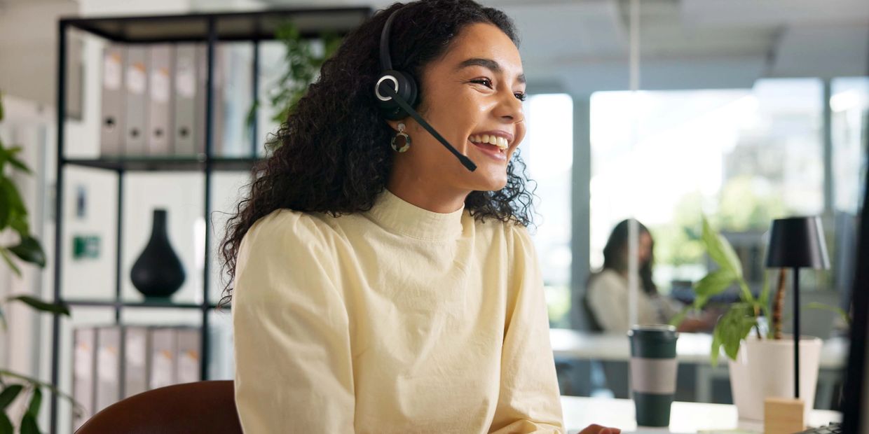 Smiling woman with headset working in a bright modern office.