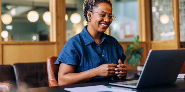Woman smiling at laptop during video call.