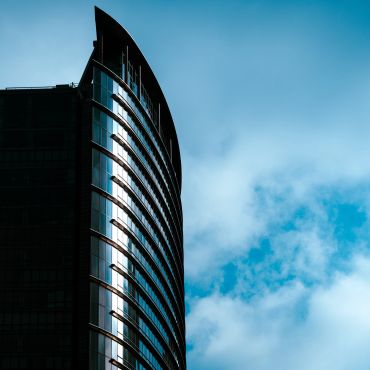 Modern curved glass building against blue sky.