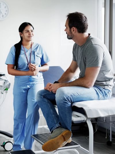 Nurse talking to a male patient in a clinic room.