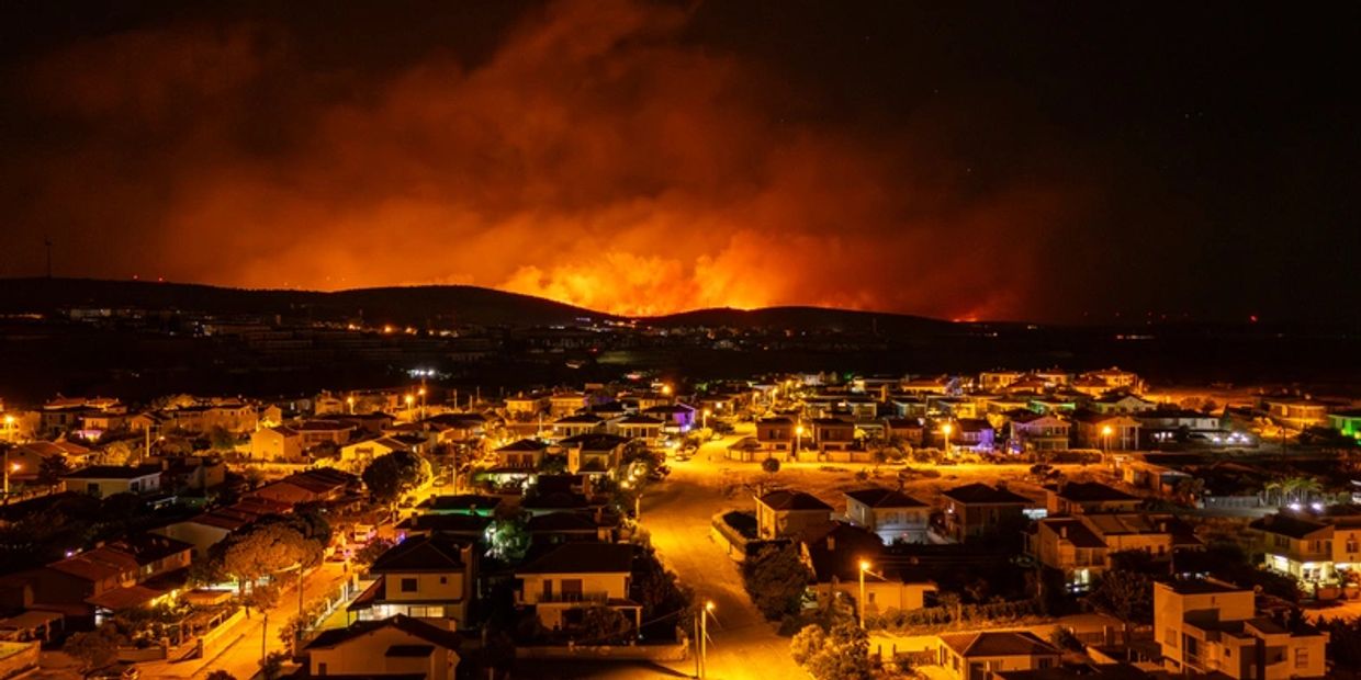 Nighttime wildfire glowing behind a suburban neighborhood.