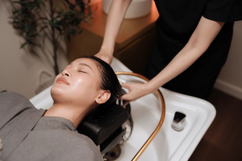 Woman relaxing during a luxurious hair wash and head spa session at a wellness center as gentle streams of warm water flow from the shower ring. The soothing sensation, paired with the tranquil atmosphere and aromatic products, helps ease stress and tension, promoting relaxation that can improve sleep quality and support overall well-being