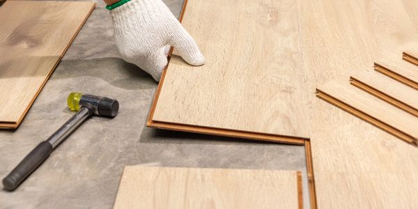 Person installing wood flooring with tools.