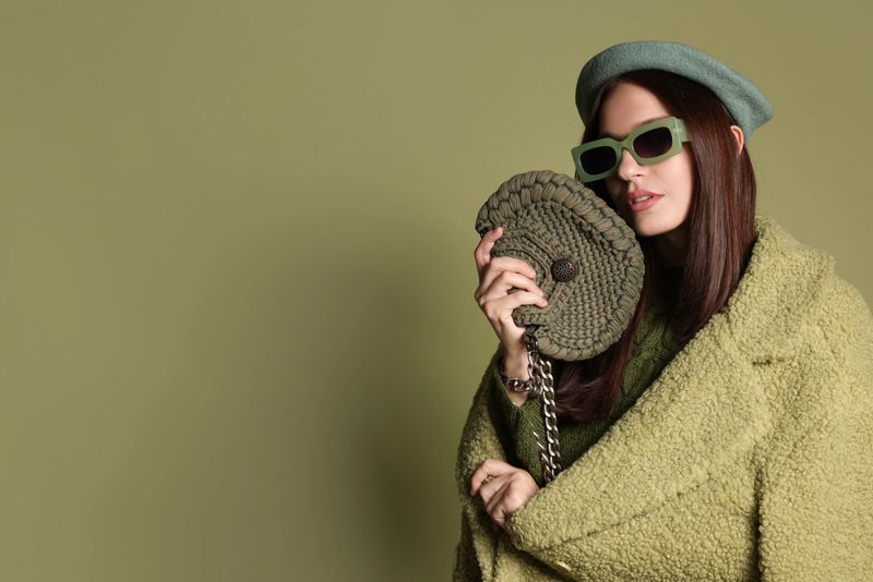 Young woman with stylish accessories on olive background, space for text