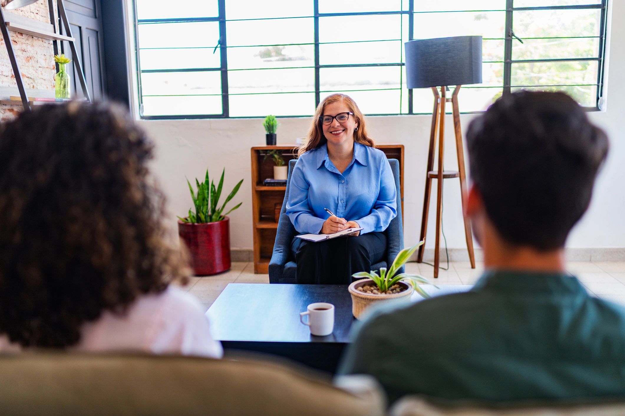 Therapist smiling and taking notes during a couple's counseling session.