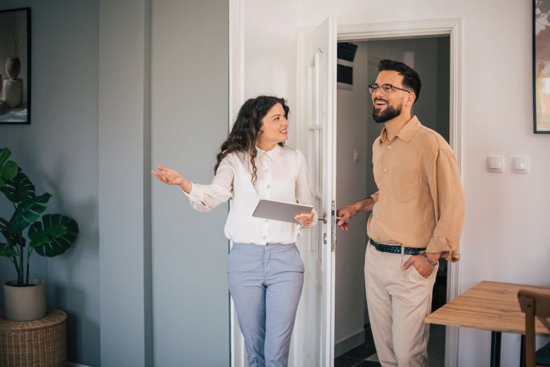 Real estate agent enthusiastically showing a modern apartment to a potential client during a property tour