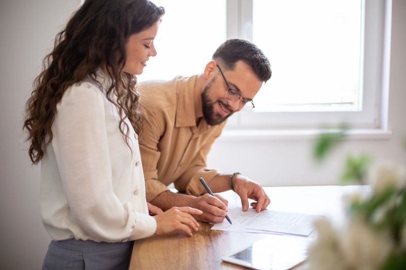 Young couple discussing and signing official documents at a bright office desk