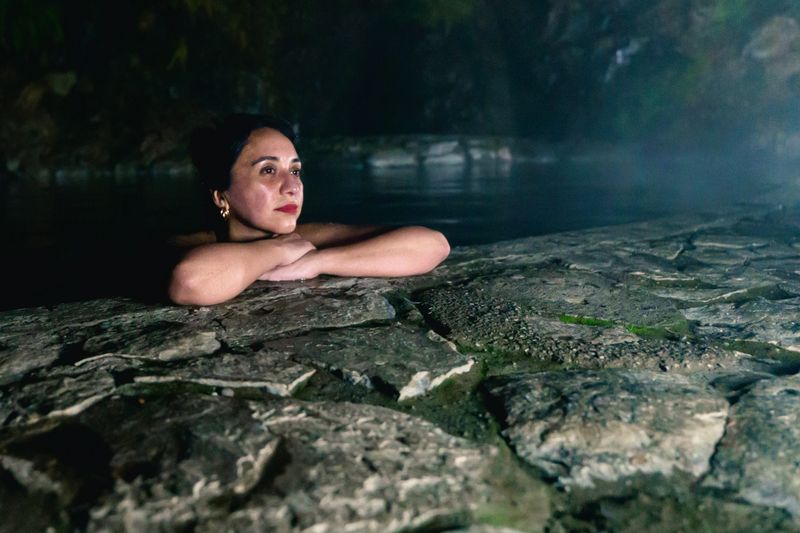 Tourist enjoying a peaceful moment in a natural hot spring under the night sky