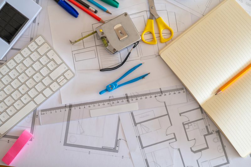 Workspace of an architect designing a sustainable building with solar panels, surrounded by blueprints, eco-friendly materials, and various drafting tools