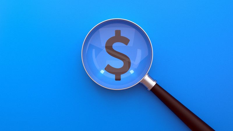A magnifying glass focuses on a Dollar Sign, symbolizing a deep dive into Finance And Economy. This minimalist Concept on a professional Blue Background is perfect for themes of Business, Investment, and financial Scrutiny. It effectively visualizes processes such as Audit, Budget review, Tax assessment, and Financial Planning. The image represents a close Examination of Wealth, Revenue, and Expense, making it an ideal visual for presentations on Market Research, Banking, and Corporate Business strategy.