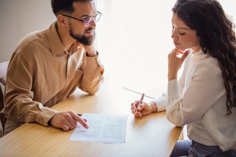Young couple reviewing and signing financial documents with advisor