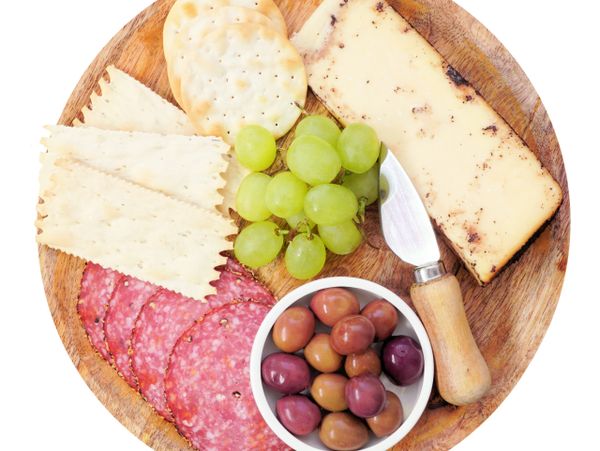 Wooden platter with cheese, salami, crackers, grapes, and olives.