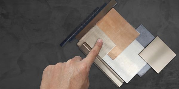 Hand pointing at metal samples or color swatches.