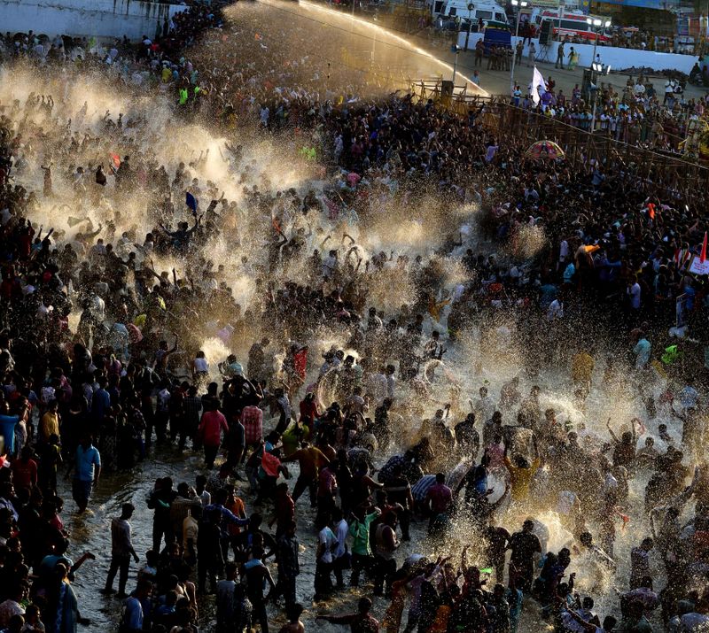 Devotees gather in overwhelming numbers as Lord Kallazhagar enters the Vaigai River during the grand Chithirai Thiruvizha in Madurai, Tamil Nadu. The air is filled with devotion and water sprays, as people celebrate.