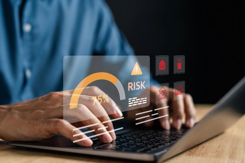 Online transaction risk warning on laptop with risk meter, cyber threat icons, financial alert signs, internet fraud, and data security breach in digital banking.