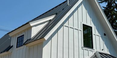 White modern farmhouse roof and windows under blue sky.