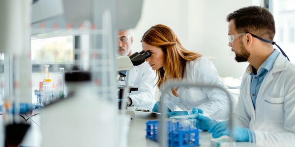 Scientists observing through a microscope in a lab.