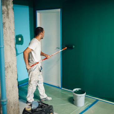 Man painting a wall teal.