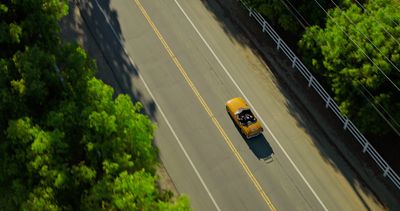 A car traveling along a tree-lined road