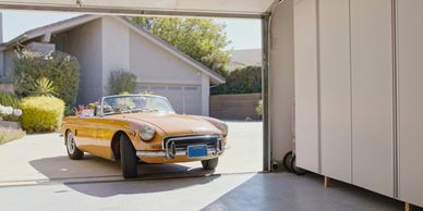 Yellow vintage convertible car parked outside a garage.