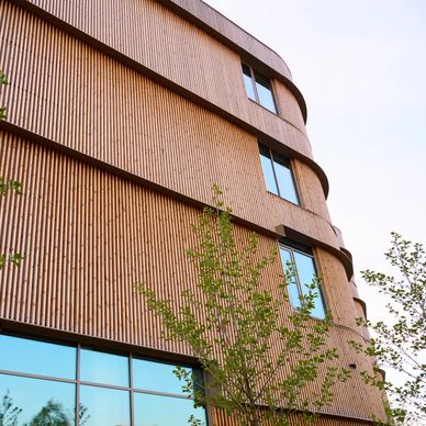 Modern building with wooden exterior and large windows reflecting the sky.
