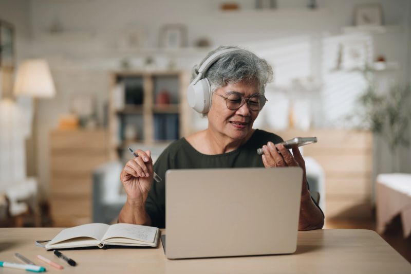 Senior woman using an AI-powered app on her smartphone to enhance her online language lesson. With a focused expression, she engages in interactive exercises and pronunciation practice, making the most of modern technology to support her learning journey and build her language skills