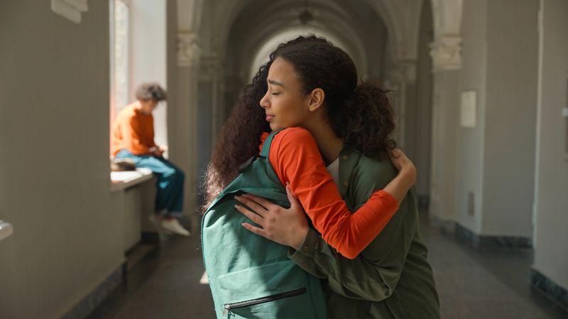Hispanic sad upset frustrated woman student walking in college university corridor hall girl female friend meeting talking supporting calming girls students hugging friendship help care problem school. High quality 4k footage