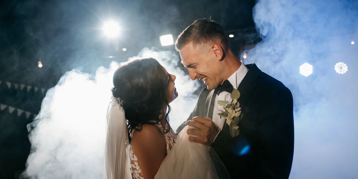 Wedding couple sharing a joyful dance amid smoke and lights.