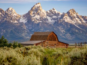 Rustic barn with snowy mountains in the background.