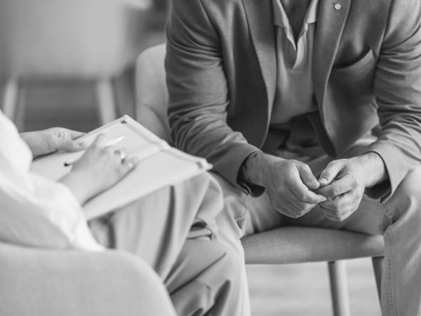Two people in a discussion, one writing notes.