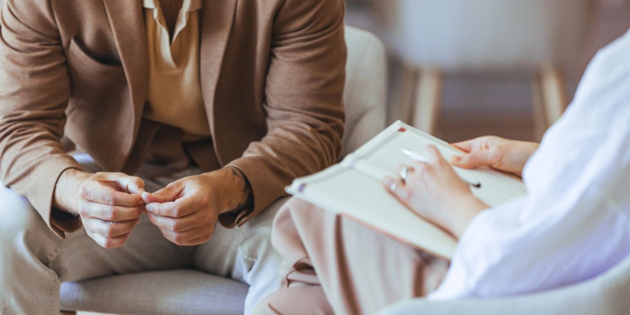 Man in a therapy session with a counselor taking notes.